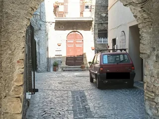 Passaggio sotto un arco in pietra, con un antico portone rosso sullo sfondo. Questo è il confine tra "Nammonte" e "Nabballe"