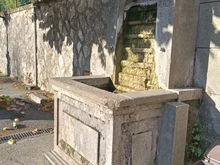 La Fontana Nova lungo Viale Trento Trieste: un fontanile in pietra con la nicchia ad arco e la vasca.