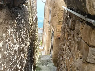 Un arco di pietra incornicia la scaletta che scende tra le case, con la vista che si apre sulla vallata.