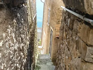 Un arco di pietra incornicia la scaletta che scende tra le case, con la vista che si apre sulla vallata.