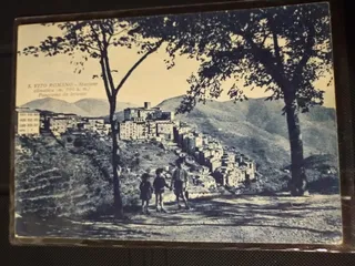 Cartolina d'epoca: "S. Vito Romano - Stazione climatica (m. 700 s. m.) - Panorama da levante", con tre bambini per mano sulla strada e il paese sullo sfondo.