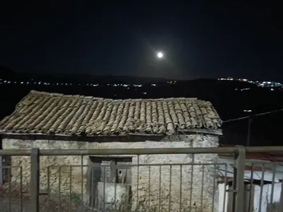 La luna illumina la valle, con le luci dei paesi all'orizzonte