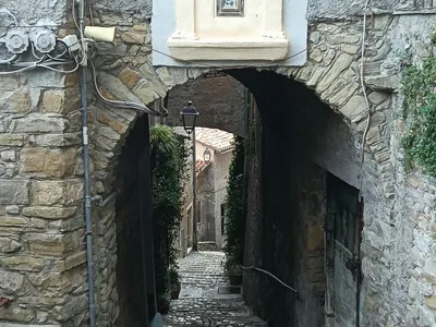 Piccola edicola sacra sopra l'arco d'ingresso a un vicolo in discesa.