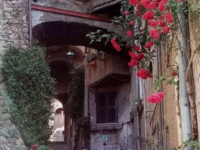 Una scalinata in pietra sale sotto gli archi tra le case, tra rose rampicanti e vasi di gerani