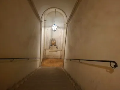 Una scala interna che scende verso una nicchia con un vaso antico.