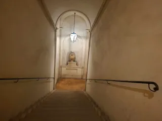 Una scala interna che scende verso una nicchia con un vaso antico.