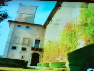 Il lato dell'ingresso principale con la torre e il muro coperto di rampicanti, in un fotogramma di una ripresa televisiva.