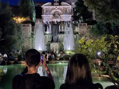 Visitatori che fotografano la Fontana dell'Organo dalle Peschiere, di sera.