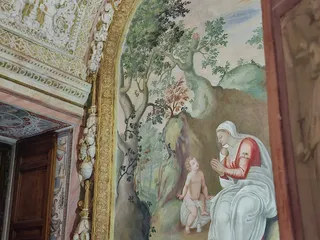 Un affresco con una figura femminile e un bambino in un paesaggio.