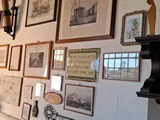 Una parete di stampe antiche e la maiolica con il motto: «Chi ama sparlare degli assenti sappia che questa mensa non fa per lui».