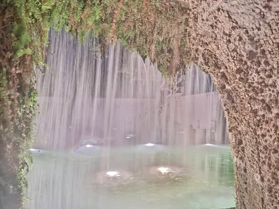 Una cascata vista dall'interno di una grotta del giardino.