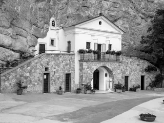 La facciata del santuario, addossata alla roccia, con la scalinata e il piazzale.