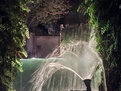 Un getto d'acqua a ventaglio illuminato nella notte.