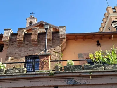 La facciata in mattoni con il piccolo campanile e la torre merlata.
