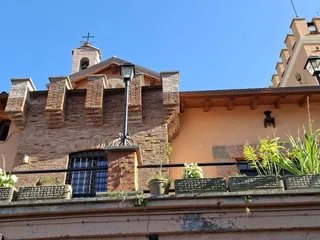La facciata in mattoni con il piccolo campanile e la torre merlata.
