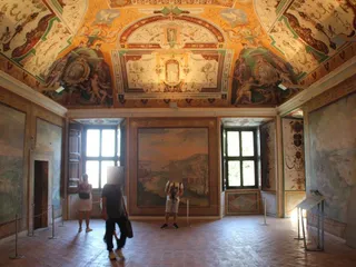 Una sala con paesaggi affrescati alle pareti e grottesche sulla volta.