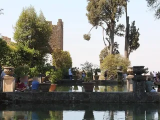 Una delle Peschiere, con alti cipressi e un'antica torre sullo sfondo.
