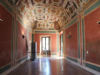 Una sala dalle pareti rosse, con la volta dipinta a finti cassettoni.