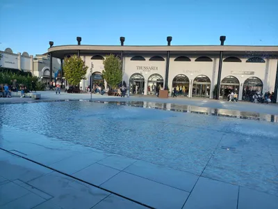 La piazza con la vasca d'acqua e i negozi sotto il portico