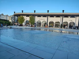 La piazza con la vasca d'acqua e i negozi sotto il portico
