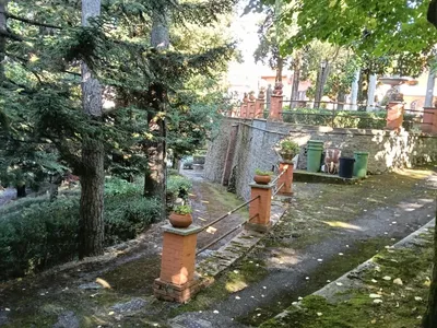I vialetti del parco tra pini, pilastri in mattoni e vasi di fiori.