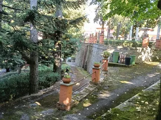 I vialetti del parco tra pini, pilastri in mattoni e vasi di fiori.