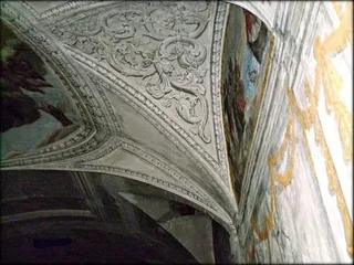 Particolare della volta: i girali in stucco bianco tra i riquadri affrescati.